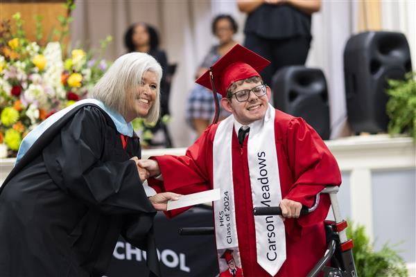 Amy Shelly Shakes Carson Meadows' hand while smiling to something off camera.